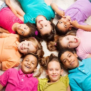 A group of children in brightly colored shirts with their heads in a circle